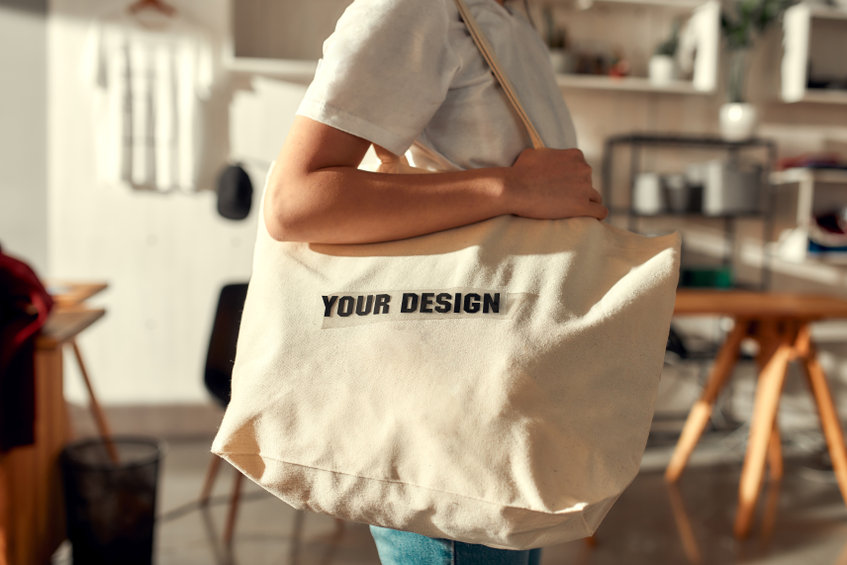 Cropped shot of female worker posing with custom shopper bag in the store.